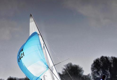 Barca a vela in mare mosso con vele blu.